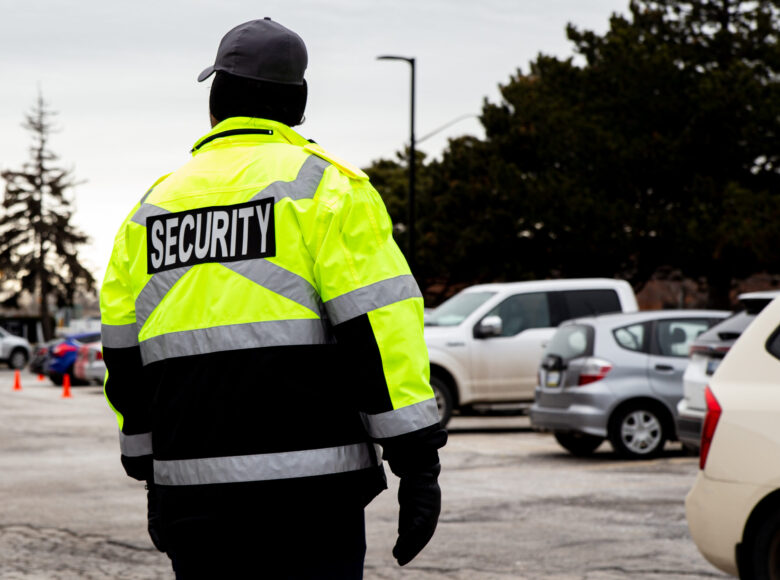 Rear view of a security guard watching over the parking area A rear view of a security guard watching over the parking area
